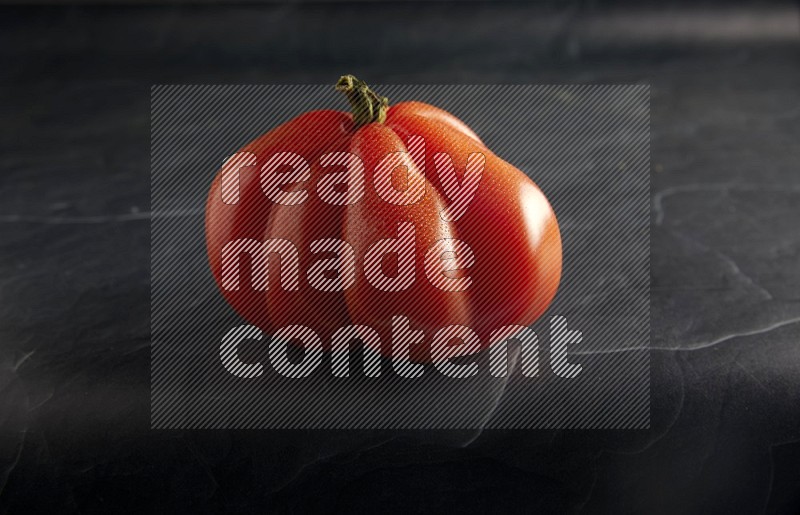 45 degree single heirloom tomato on a textured black slate background