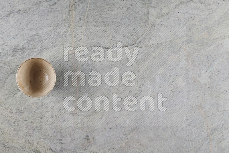 Top View Shot Of A Beige Pottery Bowl On Grey Marble Flooring