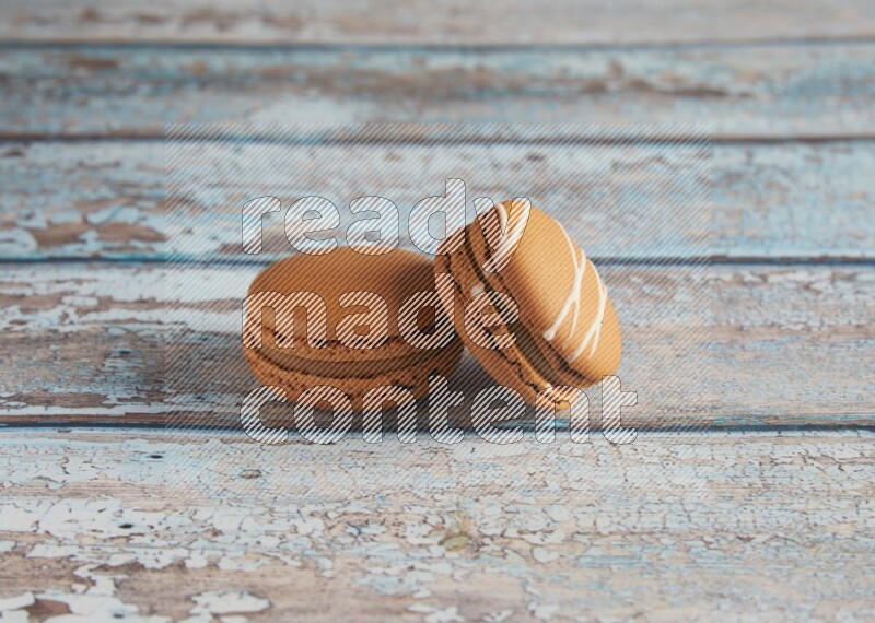 45º Shot of of two assorted Brown Irish Cream, and Brown Maple Taffy macarons  on light blue background