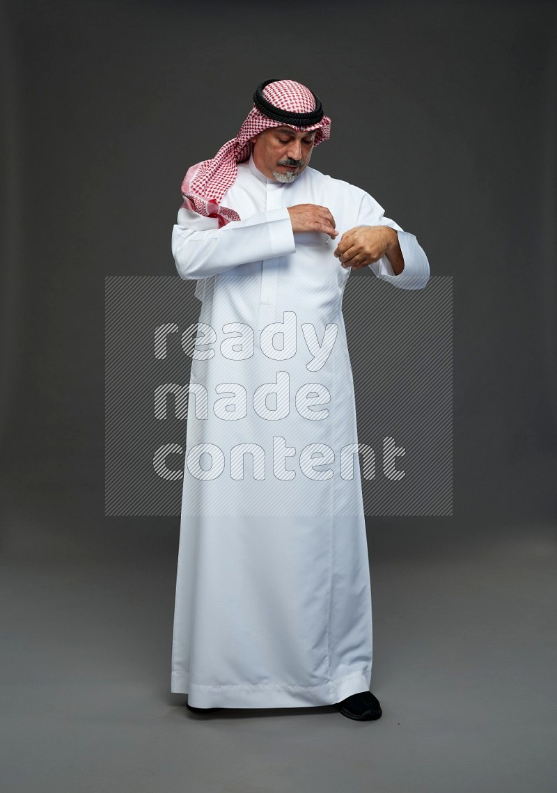 Saudi man with shomag Standing Interacting with the camera on gray background