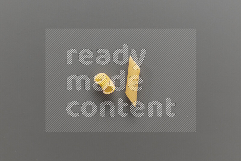Elbow pasta with other types of pasta on grey background