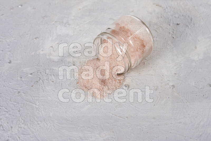 A glass jar full of fine himalayan salt on white background