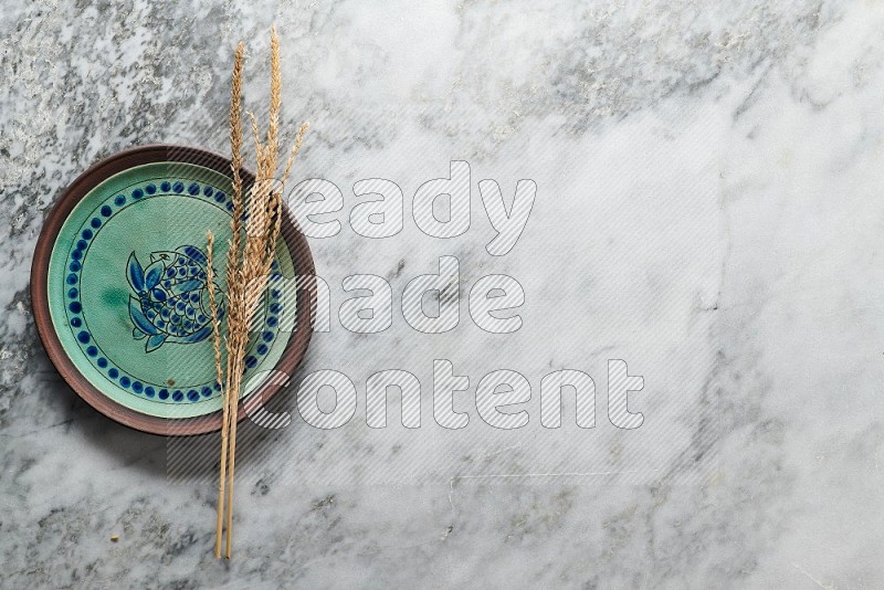 Wheat stalks on Decorative Pottery Plate on grey marble flooring, Top view