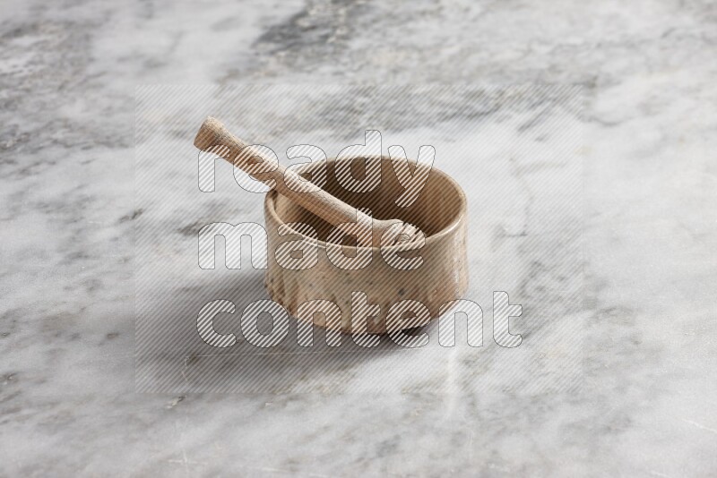 Beige pottery bowl with wooden honey dipper in it on grey marble background