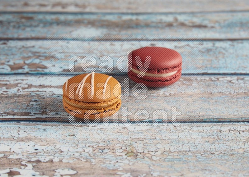 45º Shot of of two assorted Brown Irish Cream, and Red Velvet macarons on light blue background