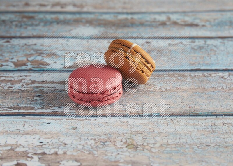 45º Shot of of two assorted Brown Irish Cream, and Pink Raspberry macarons on light blue background