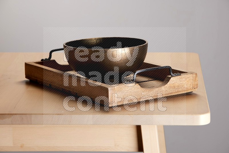 brass bowl on a light colored rectangular wooden tray with handles