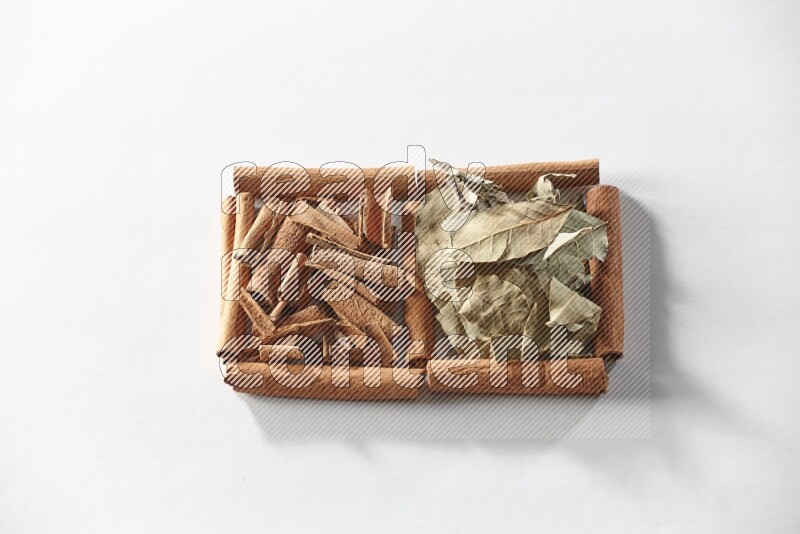 2 squares of cinnamon sticks full of cinnamon and bay laurel leaves on white flooring