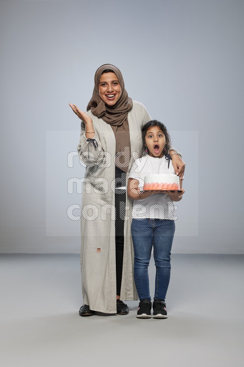 A girl giving a cake to her mother on gray background