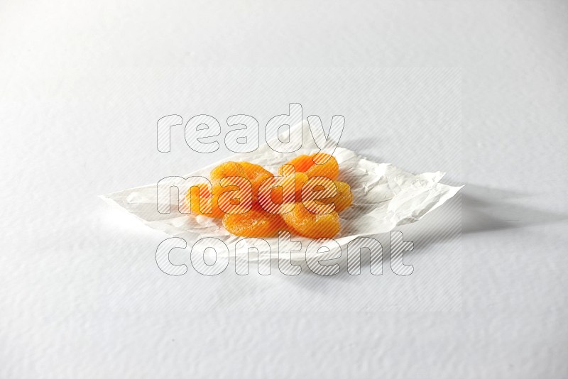 حبات من المشمش المجفف على قطعة من الورق على خلفية بيضاء