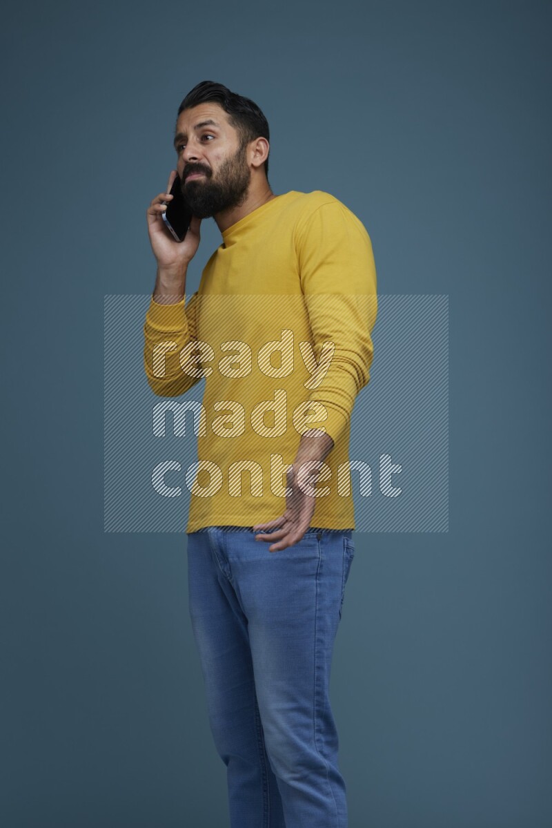 A man having a calling in a blue background wearing a yellow shirt