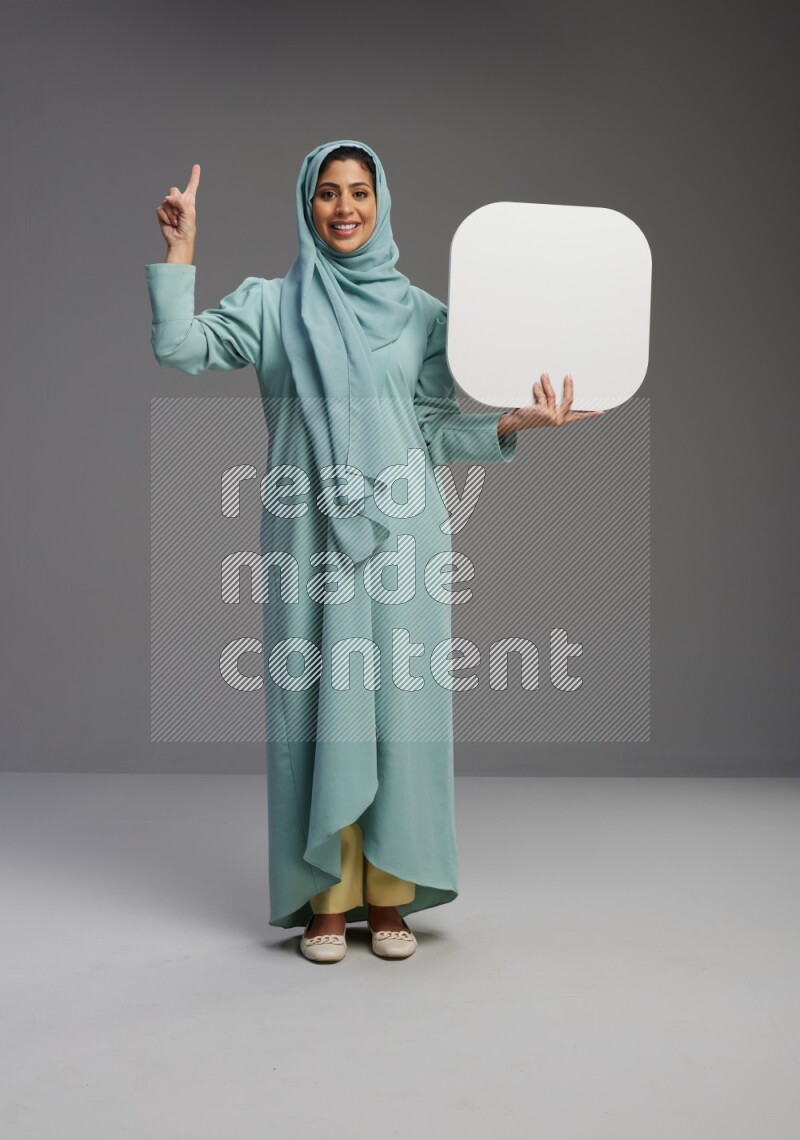 Saudi Woman wearing Abaya standing holding social media sign on Gray background