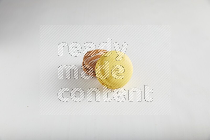 45º Shot of of two assorted Brown Irish Cream, and Yellow Lemon macarons on white background