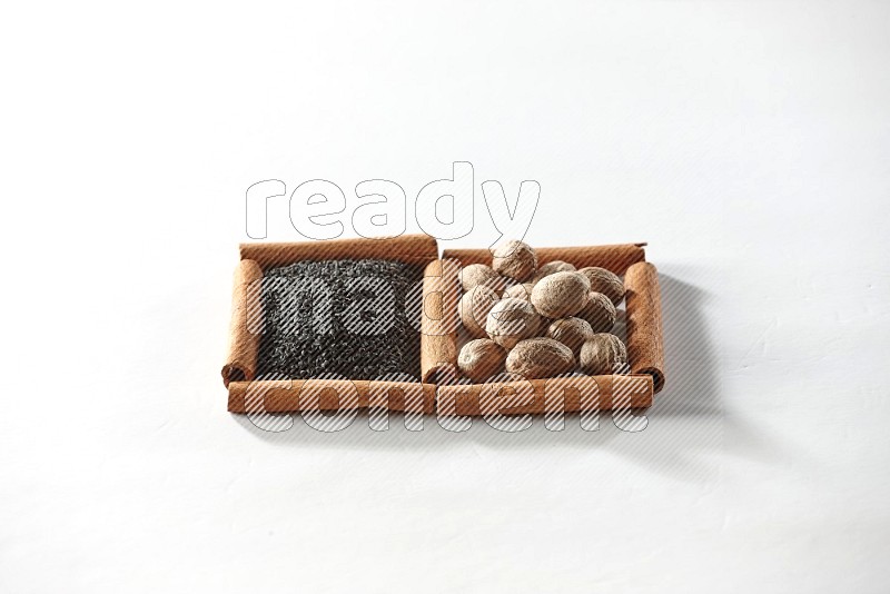 2 squares of cinnamon sticks full of black seeds and nutmeg on white flooring