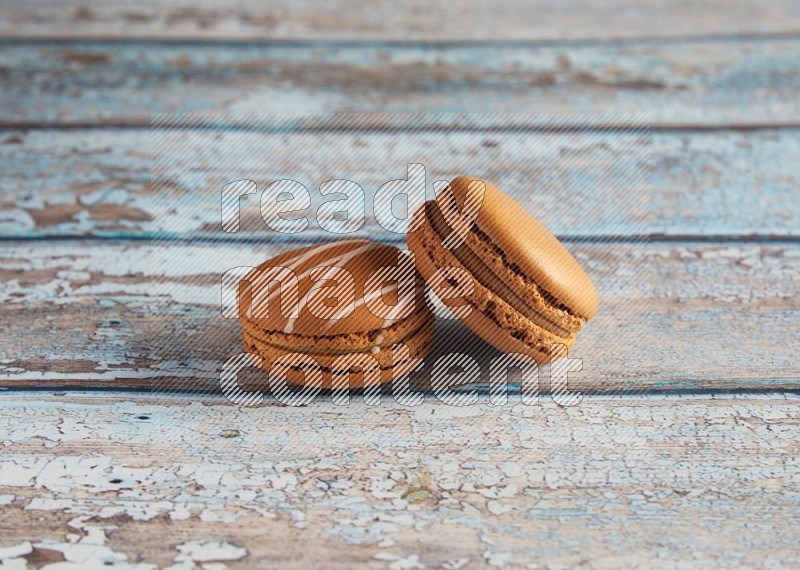 45º Shot of of two assorted Brown Irish Cream, and Brown Maple Taffy macarons  on light blue background