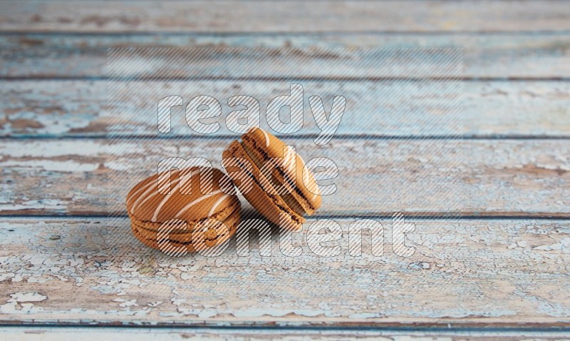 45º Shot of two Brown Irish Cream macarons on a  light blue wooden background