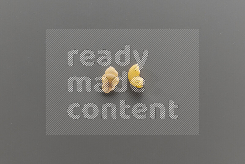 Snails pasta with other types of pasta on grey background