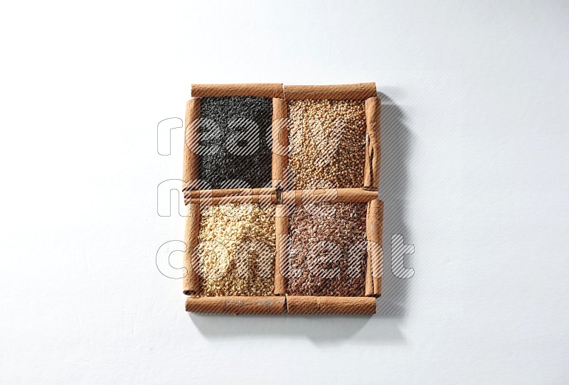 4 squares of cinnamon sticks full of black seeds, mustard seeds, flaxseeds and sesame on white flooring