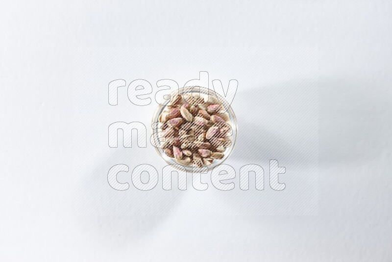 A glass bowl full of peeled pistachios on a white background in different angles