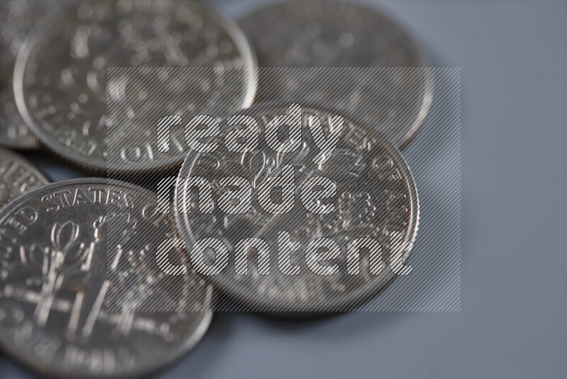 A close-up of scattered United States one dime coins on grey background