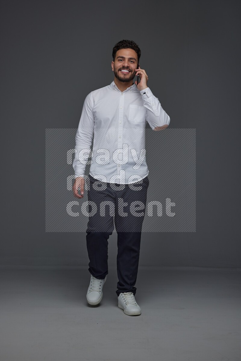 A man wearing smart casual talking in the phone eye level on a gray background