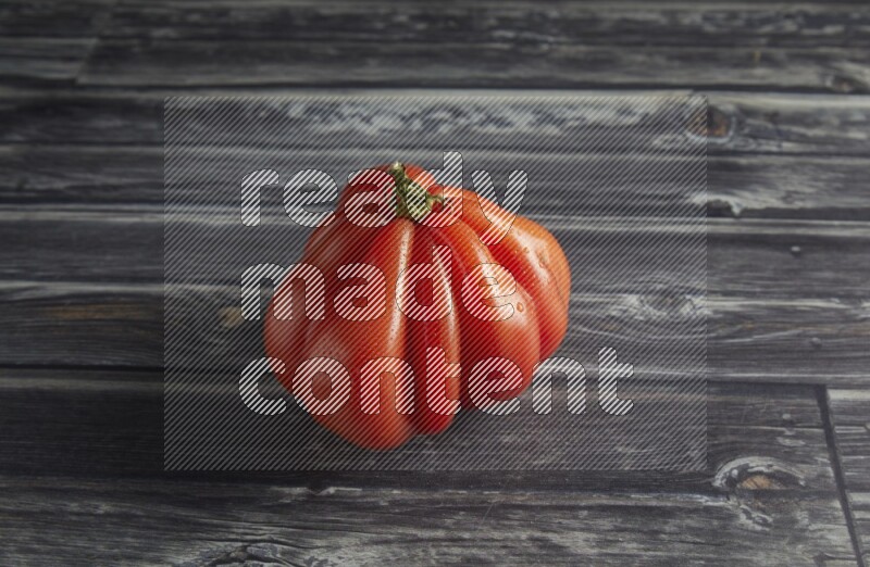 45 degree single heirloom tomato on a textured grey wooden background