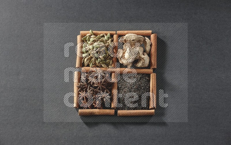 4 squares of cinnamon sticks full of tea, star anise, dried ginger and cardamom on black flooring