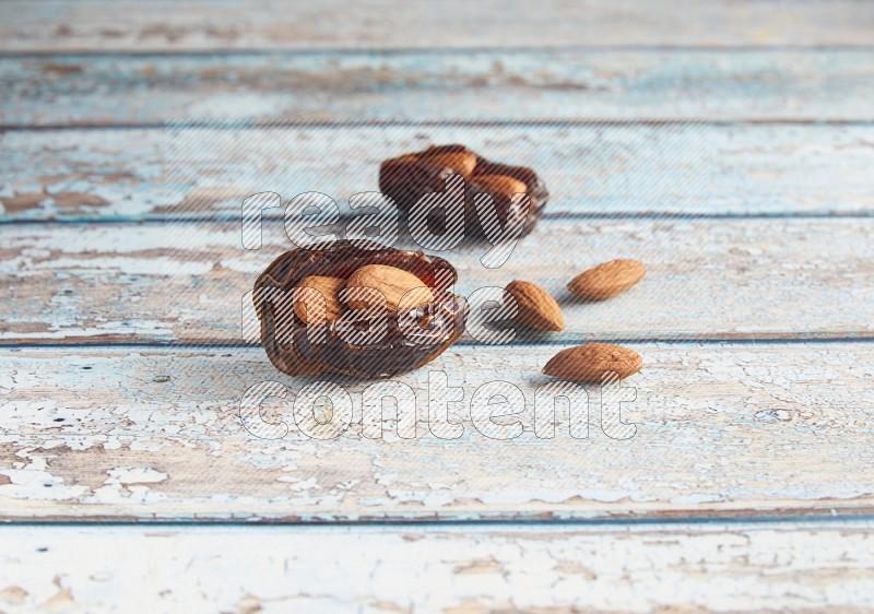 two almond stuffed madjoul dates on a light blue wooden background