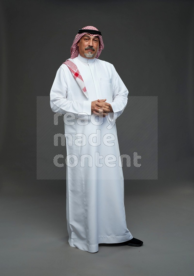 Saudi man with shomag Standing Interacting with the camera on gray background