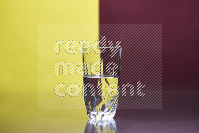 تظهر الصورة أواني زجاجية ممتلئة بالماء موضوعة على خلفية من اللونين الأصفر والأحمر الغامق