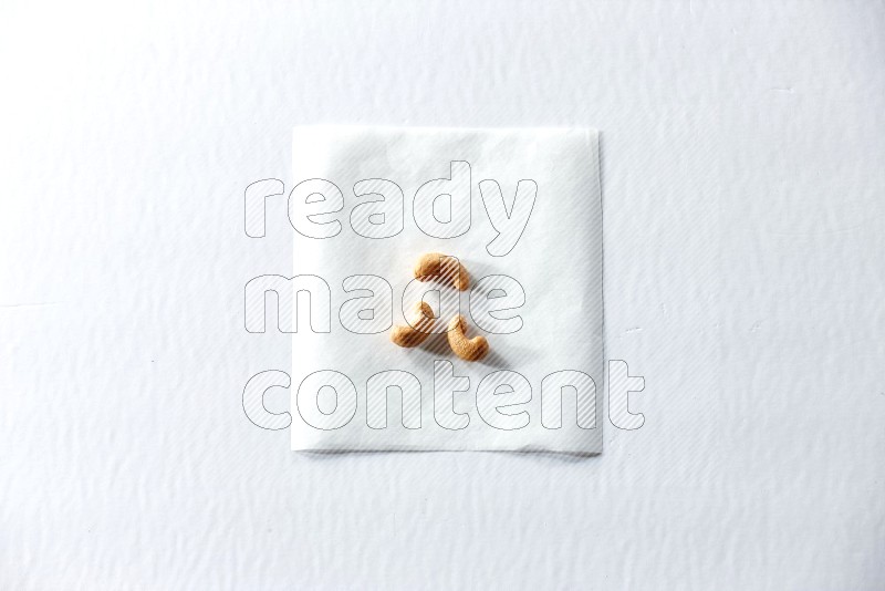 3 cashews on a piece of paper on a white background in different angles