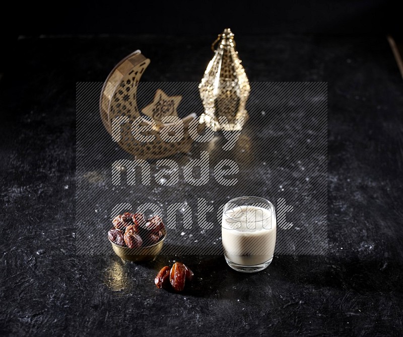 Dates in a metal bowl with dates smoothie beside golden lanterns in a dark setup