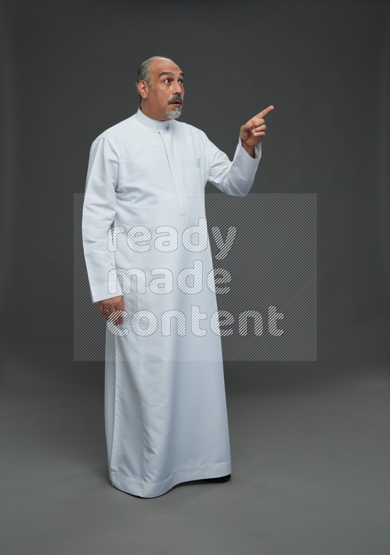 Saudi man without shomag Standing Interacting with the camera on gray background