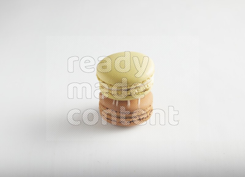 45º Shot of of two assorted Brown Irish Cream, and Yellow Lime macarons on white background