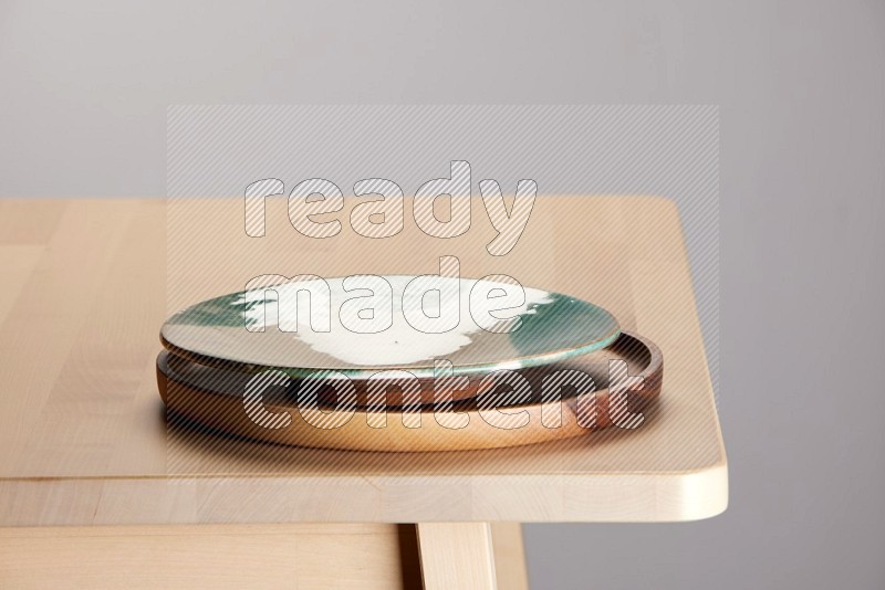 multi-colored pottery Plate placed on a light colored wooden tray on the edge of wooden table