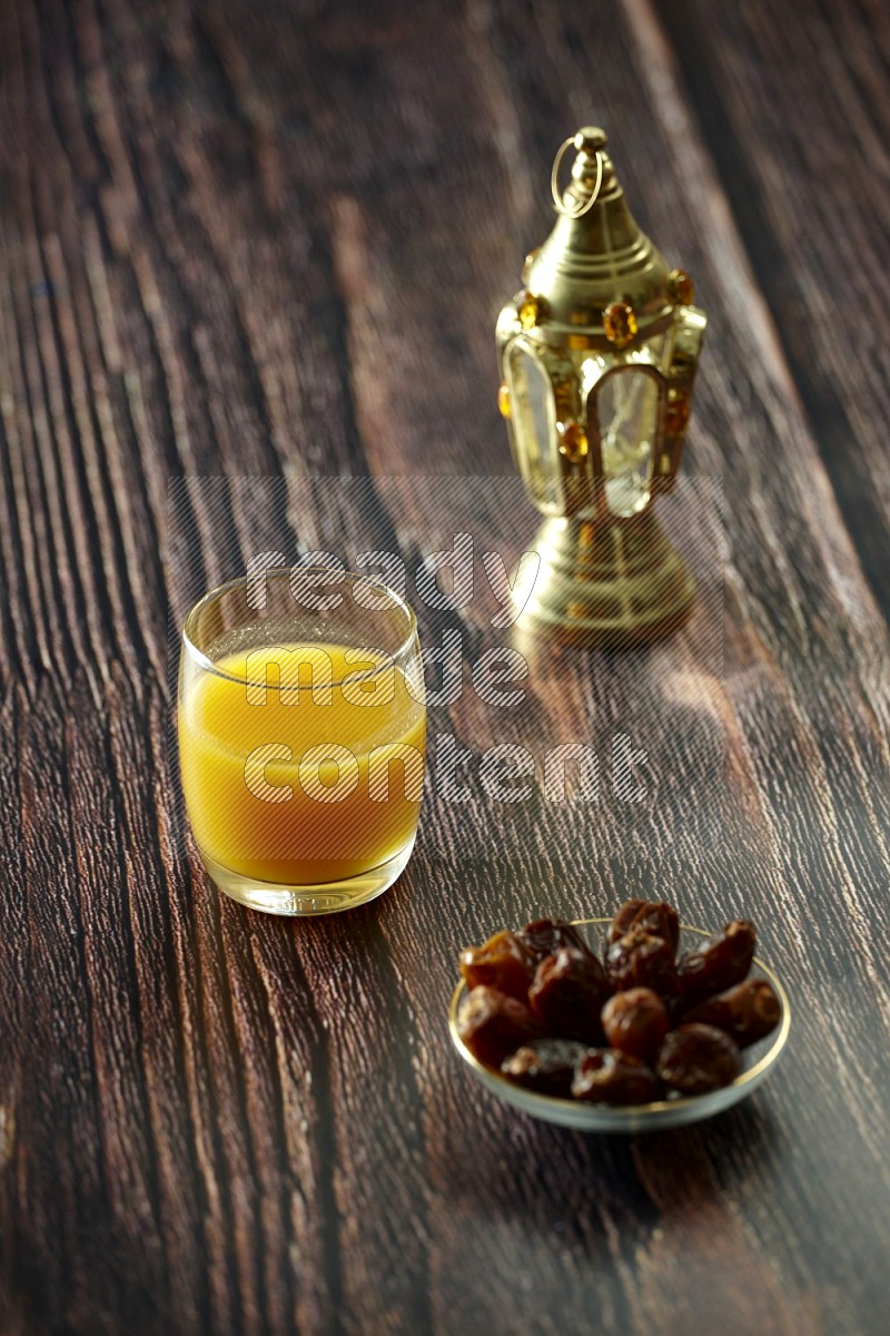 A golden lantern with drinks, dates, nuts, prayer beads and quran on brown wooden background