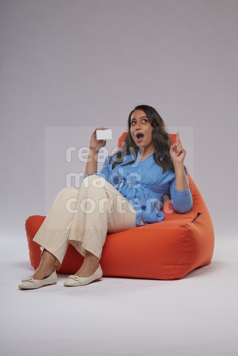 A woman sitting on an orange beanbag and holding ATM card