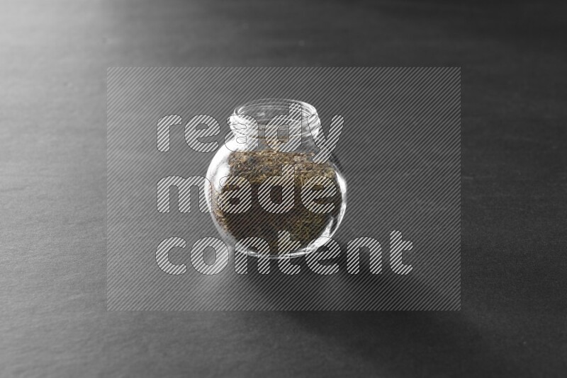 A glass spice jar full of cumin on black flooring