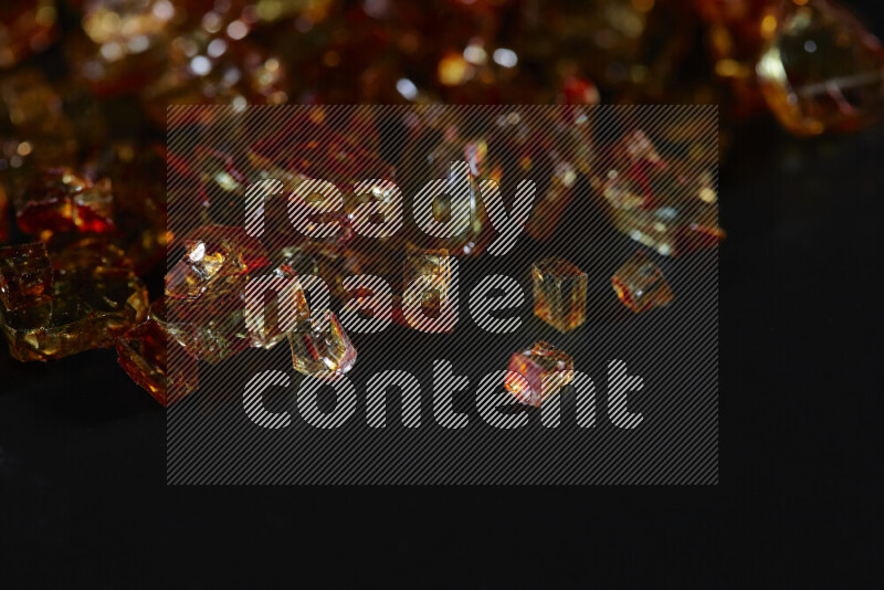 قطع زجاج برتقالية شفافة متناثرة على خلفية سوداء