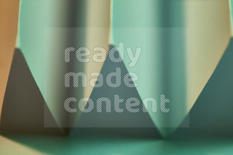 صورة مجردة مقربة تظهر طيات ورقية هندسية حادة بتدرجات اللون الأخضر مع درجات لونية دافئة