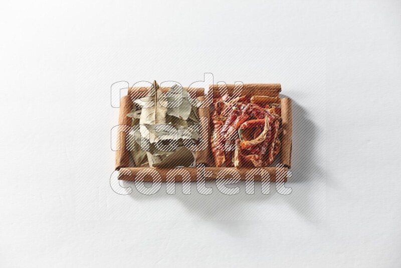 2 squares of cinnamon sticks full of dried red chilis and bay laurel leaves on white flooring