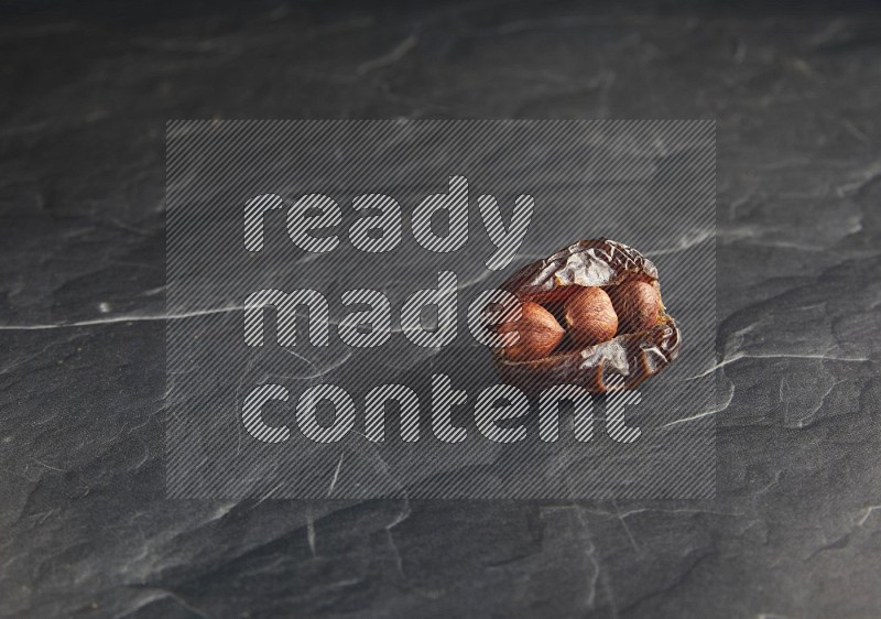 hazelnuts stuffed madjoul date on a black textured background