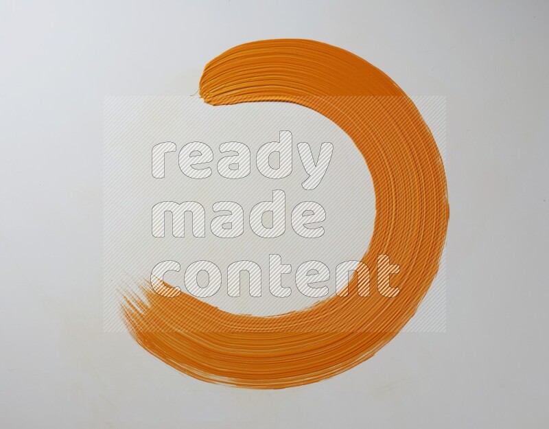 An orange circular painting brush stroke on white background