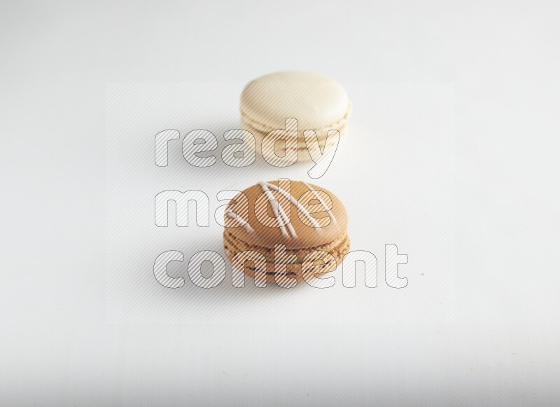 45º Shot of of two assorted Brown Irish Cream, and White Caramel fleur de sel macarons on white background