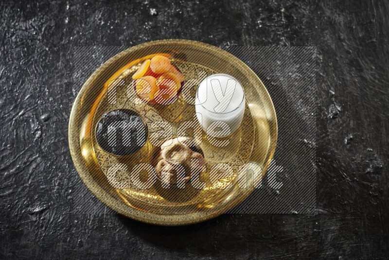 فواكه مجففة في أطباق معدنية مع السوبيا على صينية علي خلفية سوداء