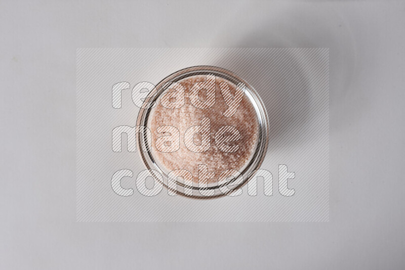 A glass bowl full of fine himalayan salt on white background