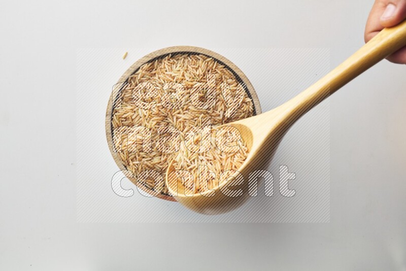Top-view shot of long grain brown rice in a container on white background