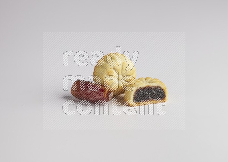 Two Pieces of Maamoul filled with date one of them is cut direct on white background