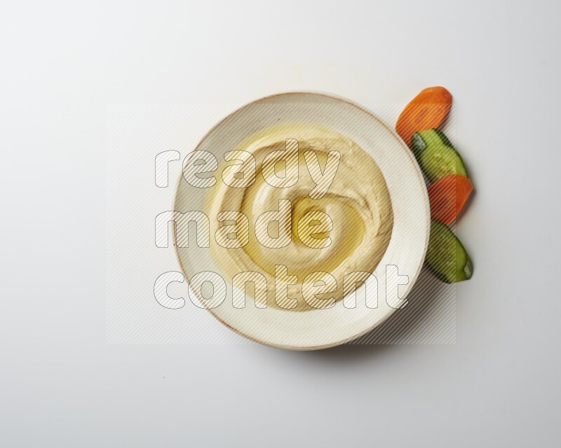 Hummus in a pottry plate garnished with olive oil on a white background