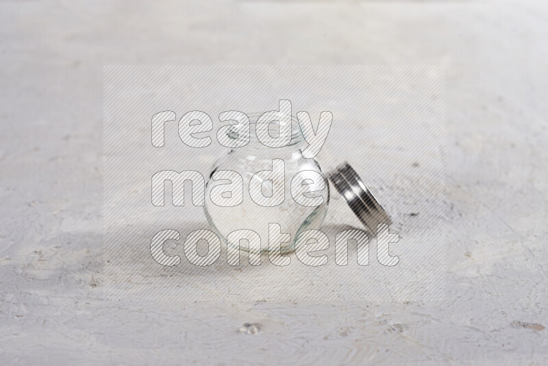 A glass jar full of coarse sea salt crystals on white background